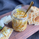 Open jar of lemon pickled garlic on cutting board with toast